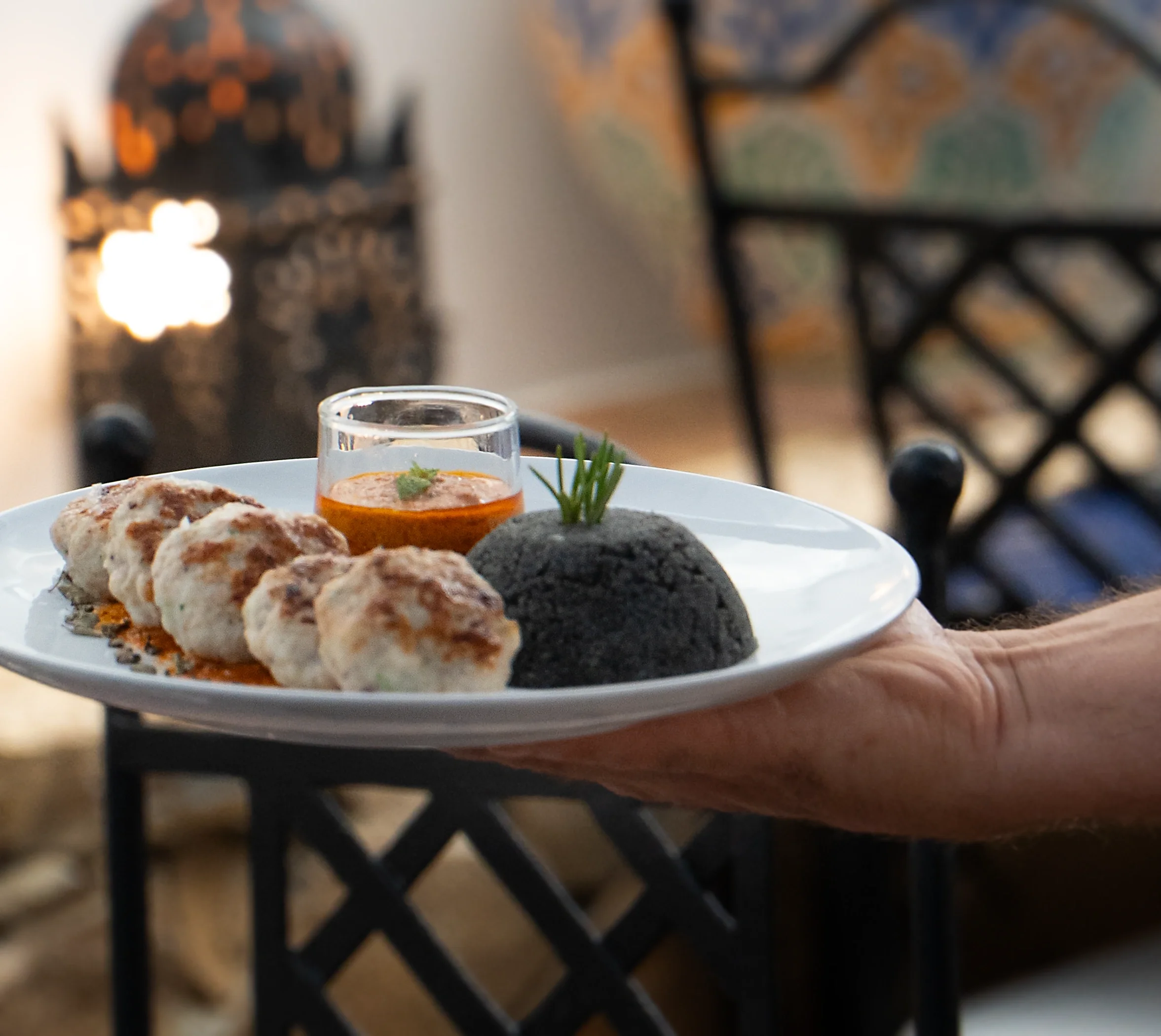 Cuttlefish keftas with sauce and black couscous on a white plate