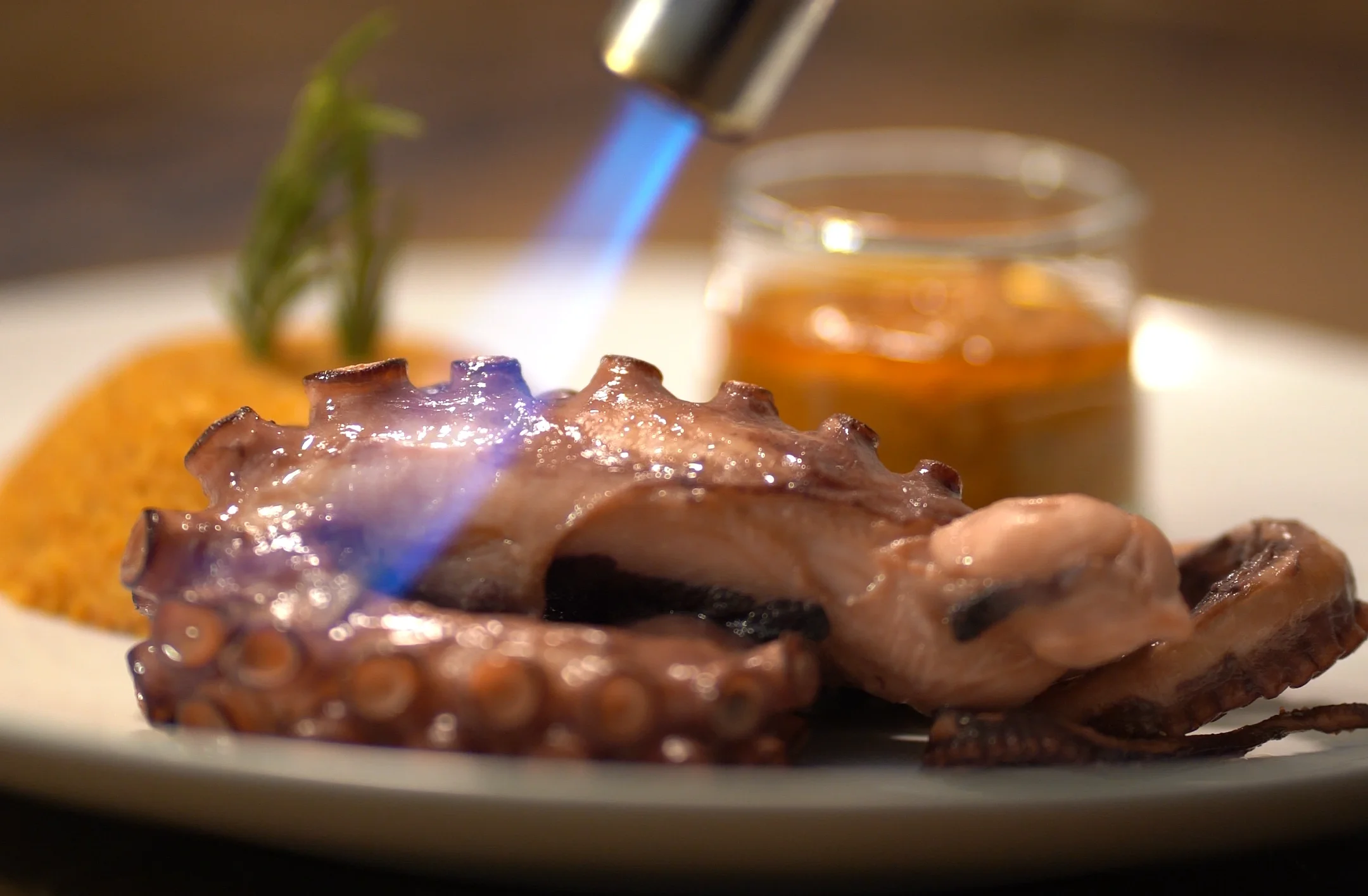 Octopus flambéed with a blowtorch alongside a golden sauce