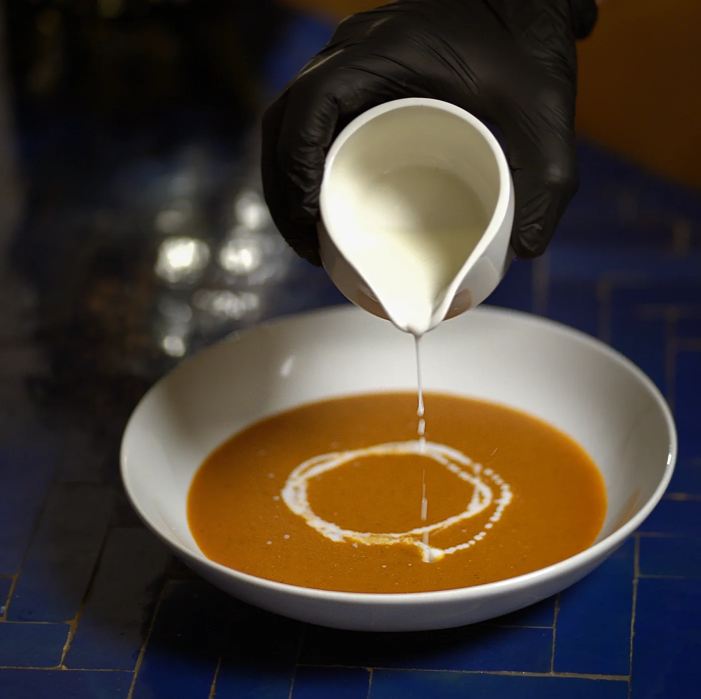Pouring a drizzle of cream over a seasonal soup