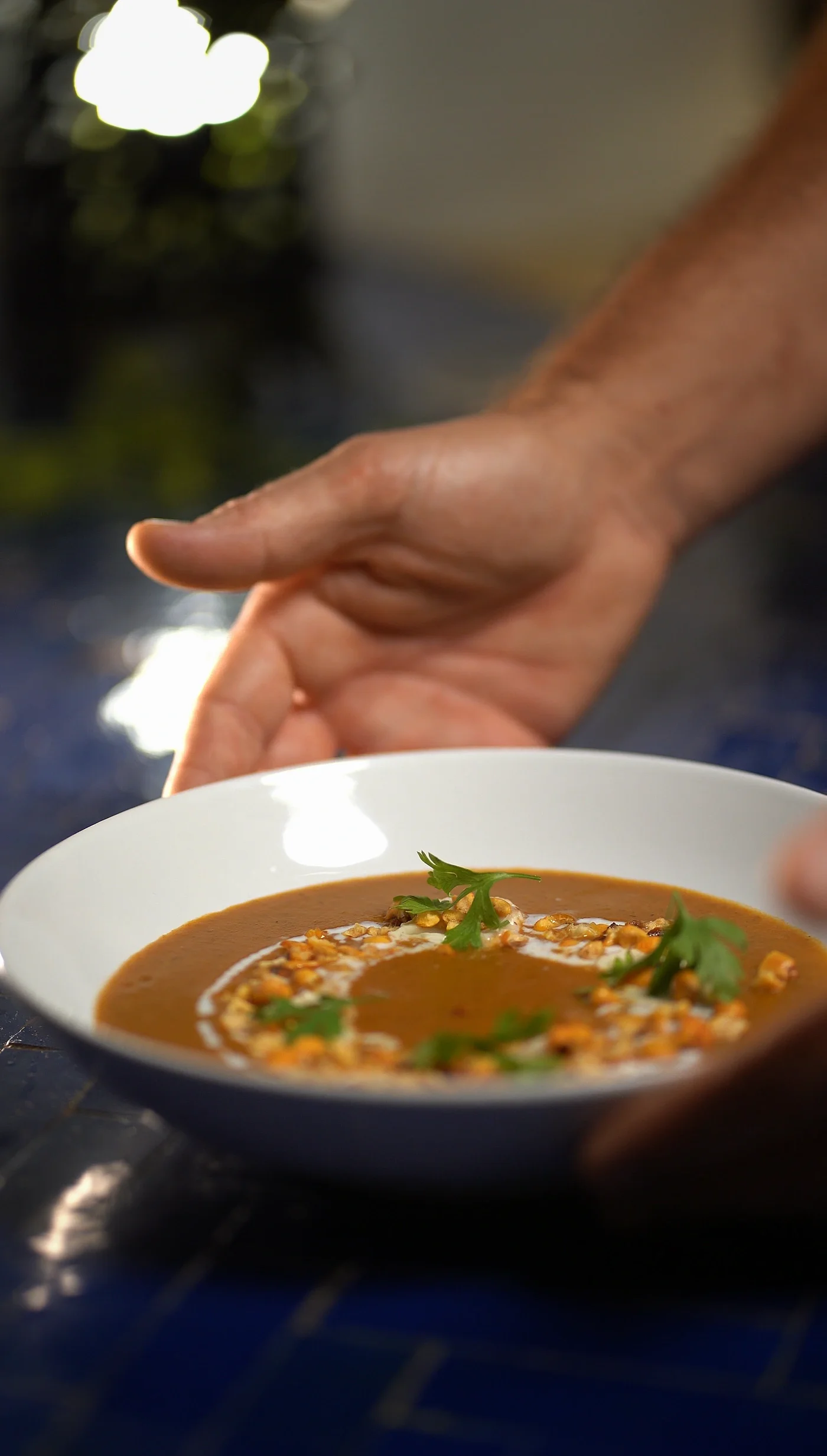 Presentation of a cream soup with toasted corn and cilantro on a table