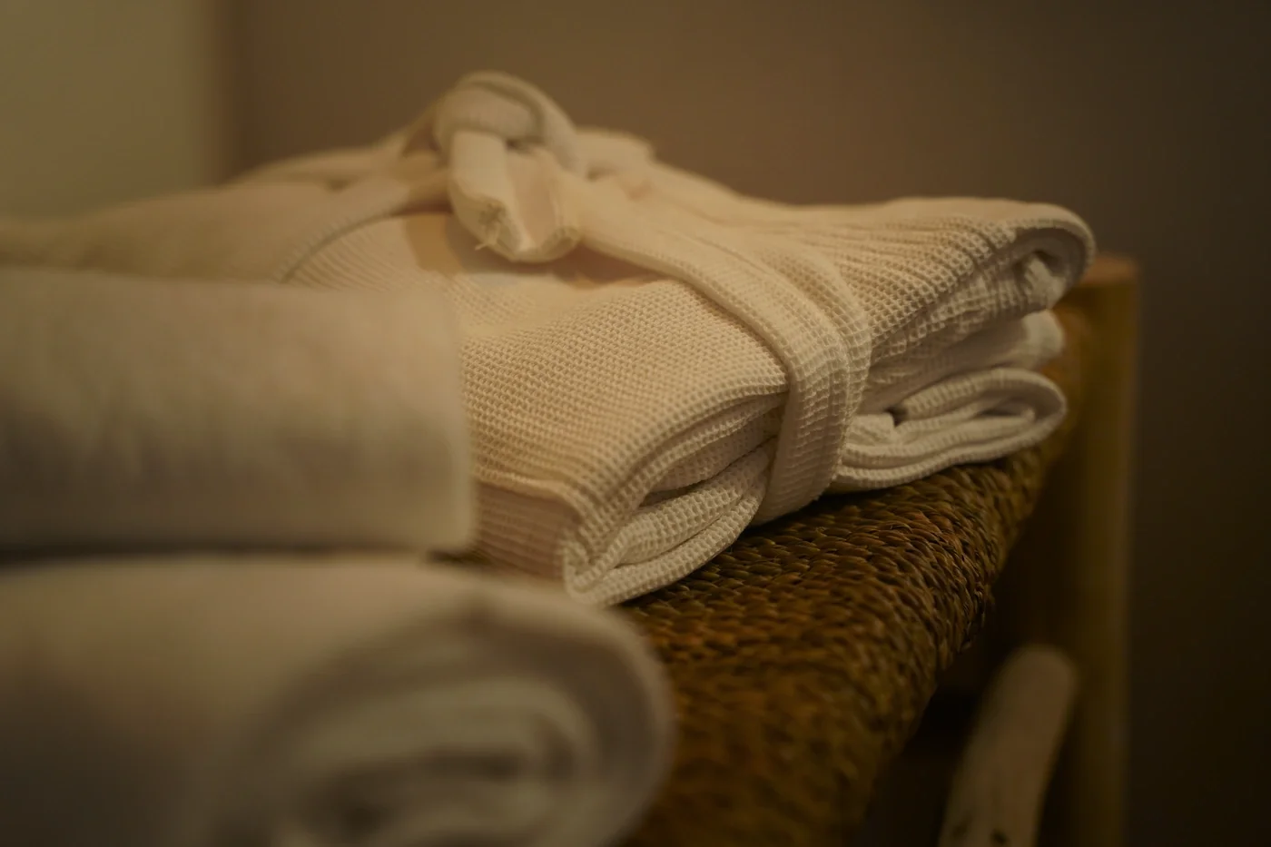 Folded towels and robes stacked on a wicker bench