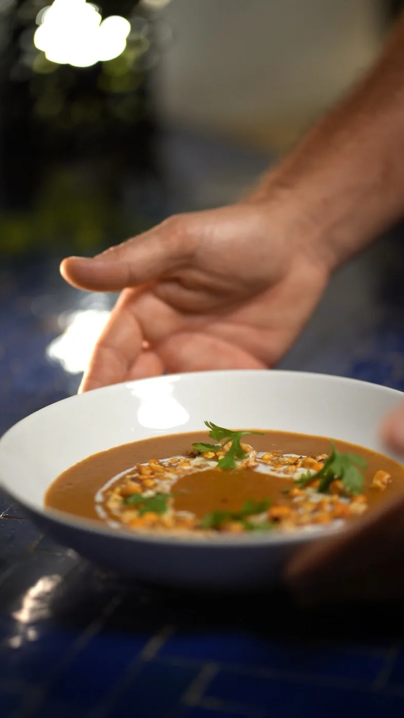 Presentación de una crema con maíz tostado y cilantro en mesa