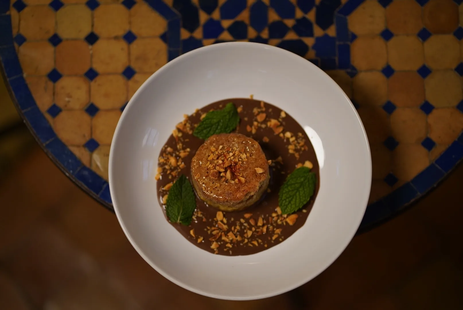 Postre con salsa de chocolate, frutos secos tostados y hojas de menta visto desde arriba